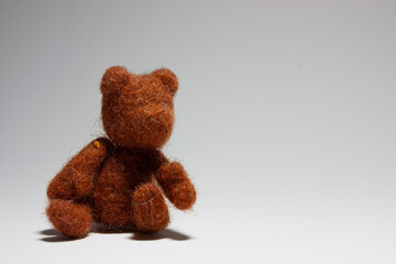 Little hand-rolled toy brown woolen teddy bear on the light background