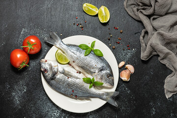 Raw dorado fish with lime, tomatoes and spices on black background top view. Sea food concept.

