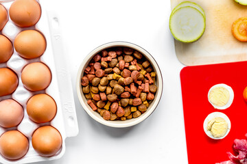 food for pets with meat and eggs on kitchen background top view