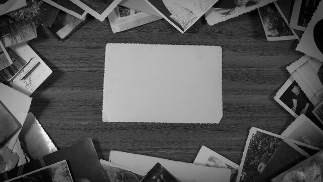 Black nad white closeup top view flatlay 4k video footage of many old vintage photographs isolated on wooden background.