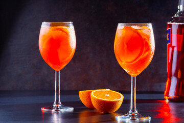 Aperol spritz cocktail on dark background. Two glasses of aperol spritz with orange slised. Summer cocktail in glass. Copy space