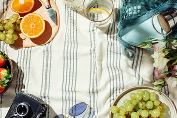 Summer picnic flatlay, fruits, berries and lemon water on striped cotton blanket