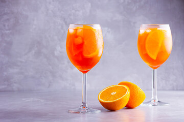 Aperol spritz cocktail on a gray background. Two glasses of aperol spritz with orange slised. Summer italian cocktail in glass. Copy space