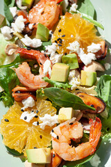 Fresh healthy summer seafood salad with spinach, avocado, oranges and feta cheese close up