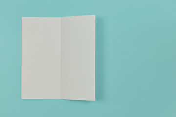 Two folded blank paper leaflet on blue background.