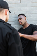 selective focus of scared african american man looking at policeman, racism concept