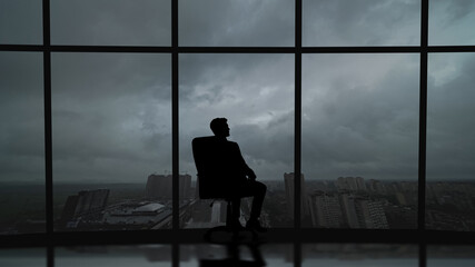 The business man is sitting in the office near the window with a scenic sky view