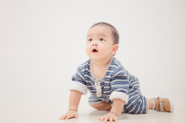 Fototapeta premium Smiling crawling asian baby boy at home on floor with white background.