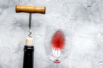 Bottle of red wine with corkscrew on white stone background