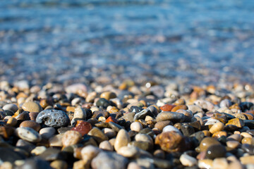 Colorful sea stones. Sea pebble / stones background/ beach rocks. Colorful summer background. Top view. Pebble in the blue water. Wet beautiful stones. Summer background. Copy space.