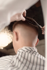 Professional barber styling with scissors and comb, Men's hairstyling and haircutting closeup in a...