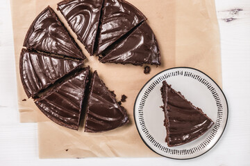  Eight slices of chocolate brownie cake on top of parchment paper on a white table.  - 364551072