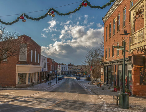Deserted small town Main Street late afternoon sun and shadows on street, storefronts, brick buildings and Christmas decorations nobody