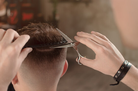 Professional barber styling with scissors and comb, Men's hairstyling and haircutting closeup in a barber shop or hair salon