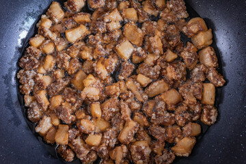 Fried crispy pork cracker. Homemade Crackling and lard (Pork oil) are fried in hot pan. It made from scrap of pork in small piece. Organic fat food.