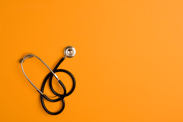 Covid-19 Coronavirus concept. Stethoscope medicine accessory, orange background with copy space....
