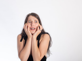 Fototapeta premium portrait of a young pretty black-haired girl on a white background. on the girl's face is an emotion of fright/horror. isolate on a white background. space for text.