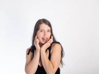 Portrait of a young black-haired girl with braces on her teeth on a white background. girl flirting with her tongue hanging out isolate on a white background. space for text.