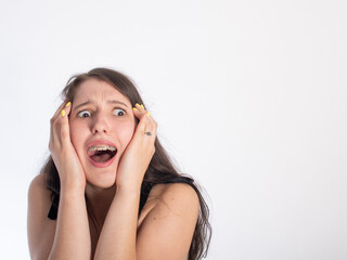portrait of a young pretty black-haired girl on a white background. on the girl's face is an emotion of fright/horror. isolate on a white background. space for text.