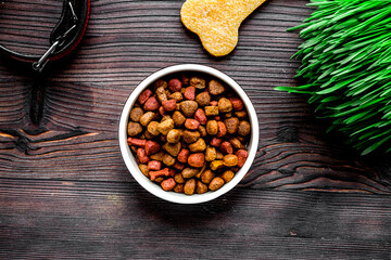 dry dog food in bowl on wooden background top view