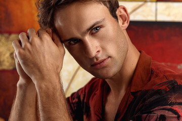 Portrait of young man with very handsome face in casual shirt against blurred background