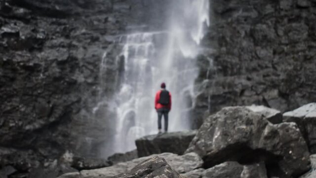 Man Standing On Rocks Under Fossa Waterfall