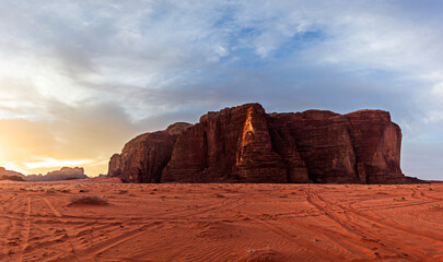 Amazing view of red sand desert landscape with rocky mountain during hot dry day in bright sunlight with cloudy blue sky