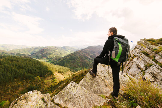 Back view of female hiker in trekking boots standing on rock and enjoying magnificent scenery of highlands in Hoces del Esva