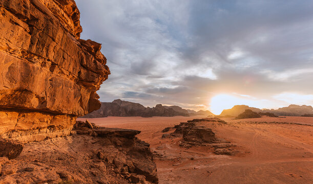 Amazing View Of Red Sand Desert Landscape With Rocky Mountain During Hot Dry Day In Bright Sunlight With Cloudy Blue Sky