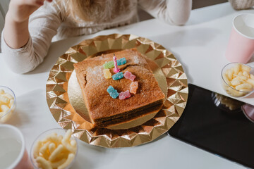 From above view of tasty birthday cake decorated with candle and jelly candies placed in shape of number five on table in room