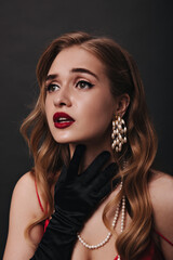 Fototapeta premium Portrait of emotional nice lady with red lips. Snapshot of sensual girl in red satin top posing on black isolated background