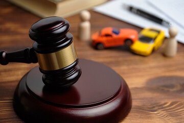 The concept of a car owner accident lawsuit. Judge hammer next to car models and documents.