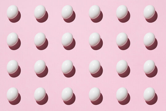 Top view of seamless background of brown and white eggs placed on pink surface in studio