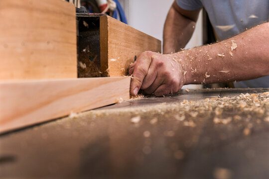 Low angle of closeup unrecognizable carpentry master milling timber using modern electric machine in light contemporary workshop