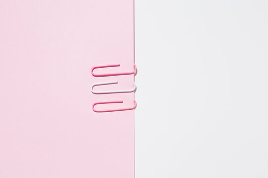 Top view of white and pink paper clips arranged on colorful background showing concept of uniqueness