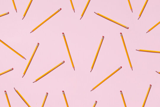 Top view of seamless background of pencils chaotically scattered on pink surface
