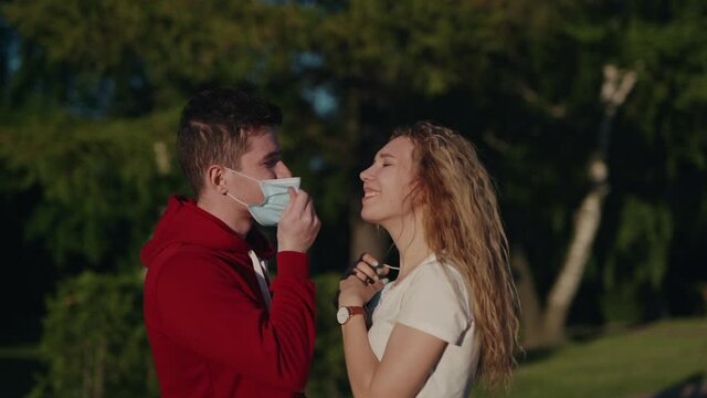 Young man and woman take off medical mask and kiss. Pandemic is over. Finally end of quarantine. Pretty couple date after long self isolation. Health care and medical concept. Happy people.