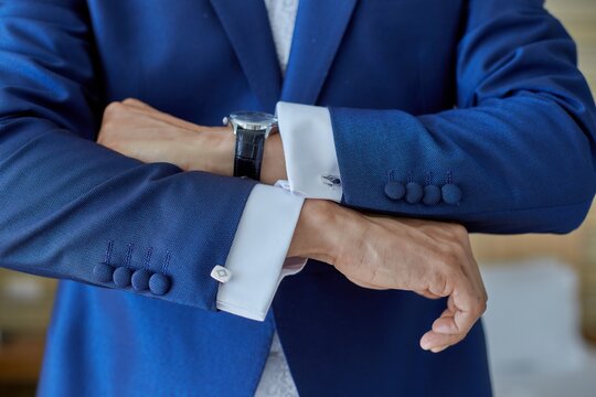 Crop fiance in classy suit standing in bright living room of modern apartment during wedding fees