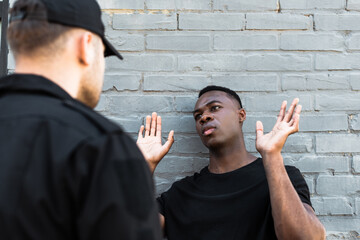 selective focus of african american man with raised hands looking at policeman, racism concept