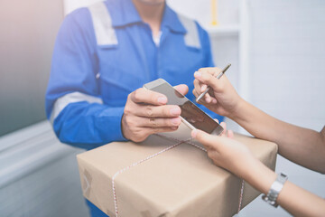 Delivery,mail and shipping,delivery man Checking Portable Device with Asian woman sign in digital Smartphone before receiving parcel or receive package,she appending signature in mobile phone at home.