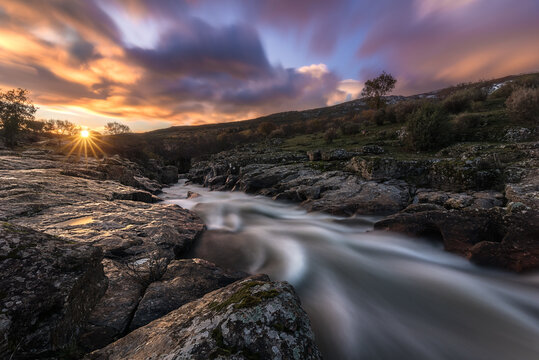 Picturesque view of mountain river streaming through rocky cliffs in calm evening during sunset in autumn