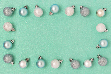 Border frame made of Christmas balls on a turquoise shiny textured background. Festive concept with place for text.
