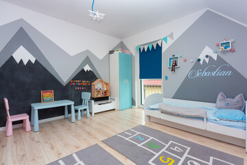 Children bedroom for a boy and a girl with painted mountains on the walls