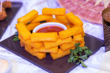 
fried muzarella sticks with red sauce with fresh parsley on event table