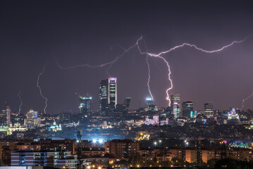 Amazing panoramic view of modern city with contemporary buildings and skyscrapers under dark night sky illuminated by plenty of lightnings