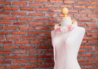 Copy space banner of manikin with rose and measuring tape, textile and fashion designing concept, in home office studio working design clothing and dress , with red brick wall texture background