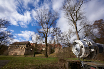Hydrant in front of a green meadow, old cloister buildings in the background, blue sky with white...