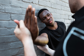 Selective focus of injured African American man looking at policeman touching hand, racism concept