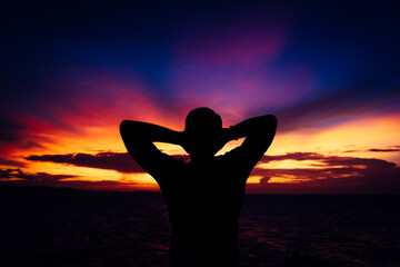 Silhouette of a happy young man on a sunset background.