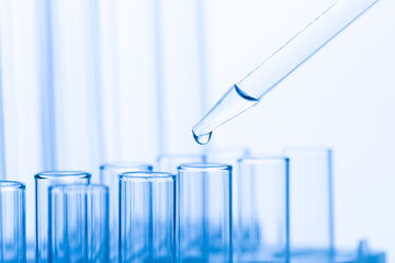 pipette with a drop and scientific laboratory test tubes in a research laboratory.